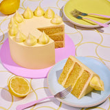 Classic Lemon Drizzle Cake by Crumbs & Doilies with three layers, lemon buttercream, meringue decoration, and fresh lemon zest.